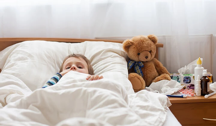 Kind liegt krank im Bett Halsschmerzen behandeln
